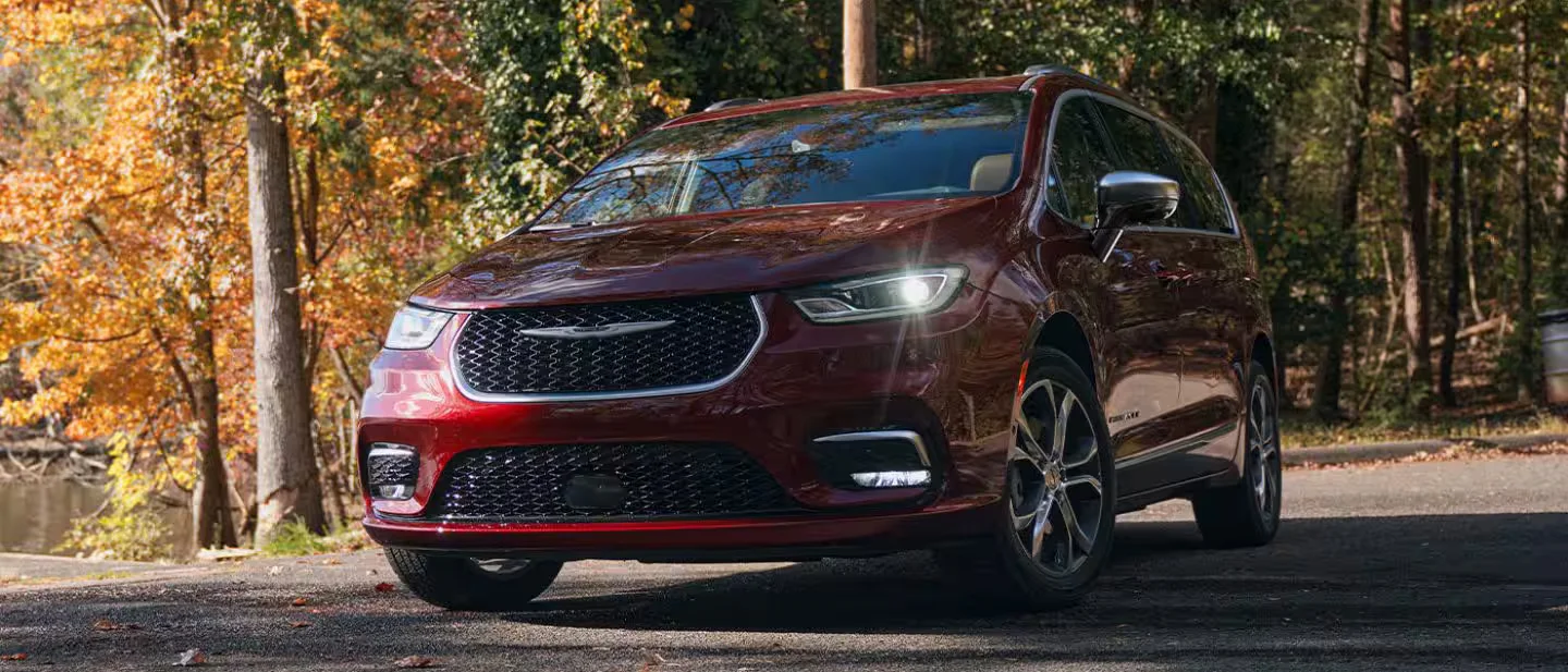 2026 Chrysler Pacifica red minivan parked near autumn trees in a front three-quarter exterior view