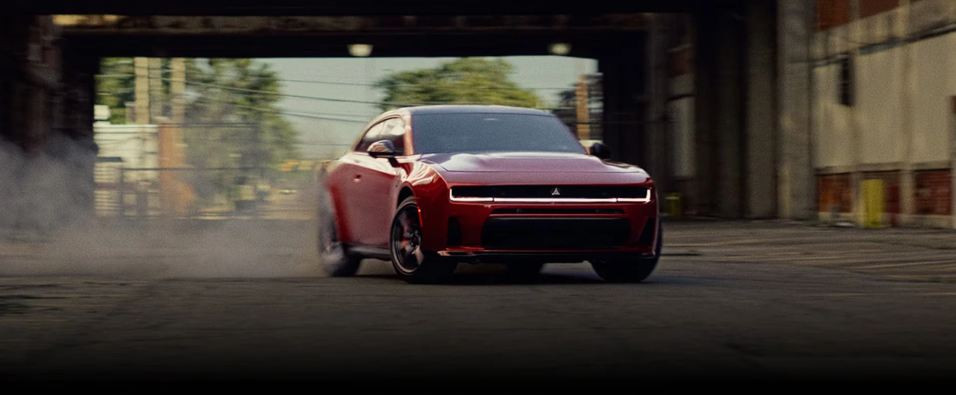 2026 Dodge Charger red front view driving through an industrial setting
