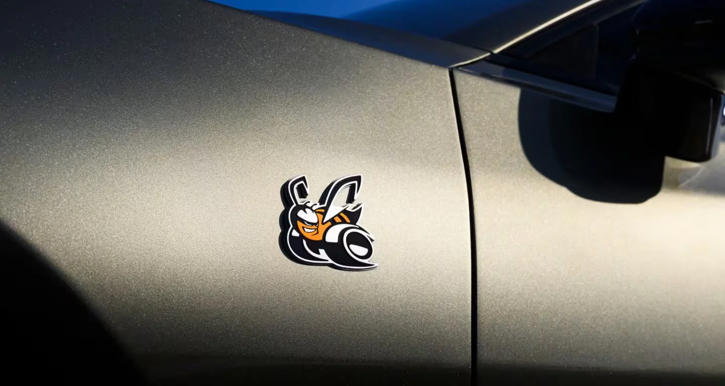 Close-up of the 2026 Dodge Charger Scat Pack bee badge on green exterior paint.
